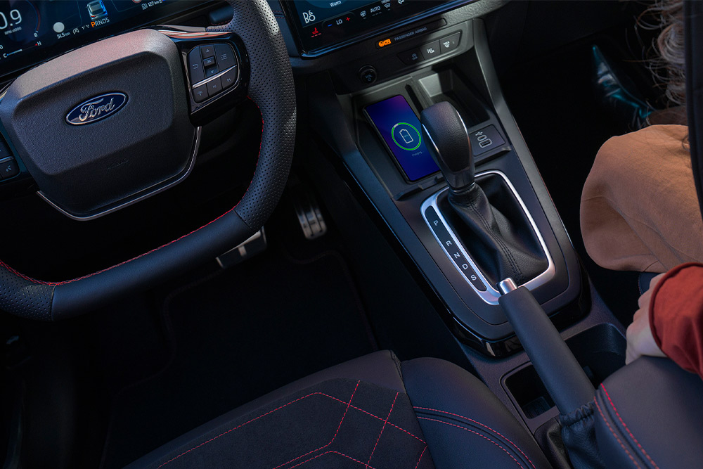 Uma vista interior de um carro híbrido leve da Ford, incluindo volante e alavanca de câmbio automática.