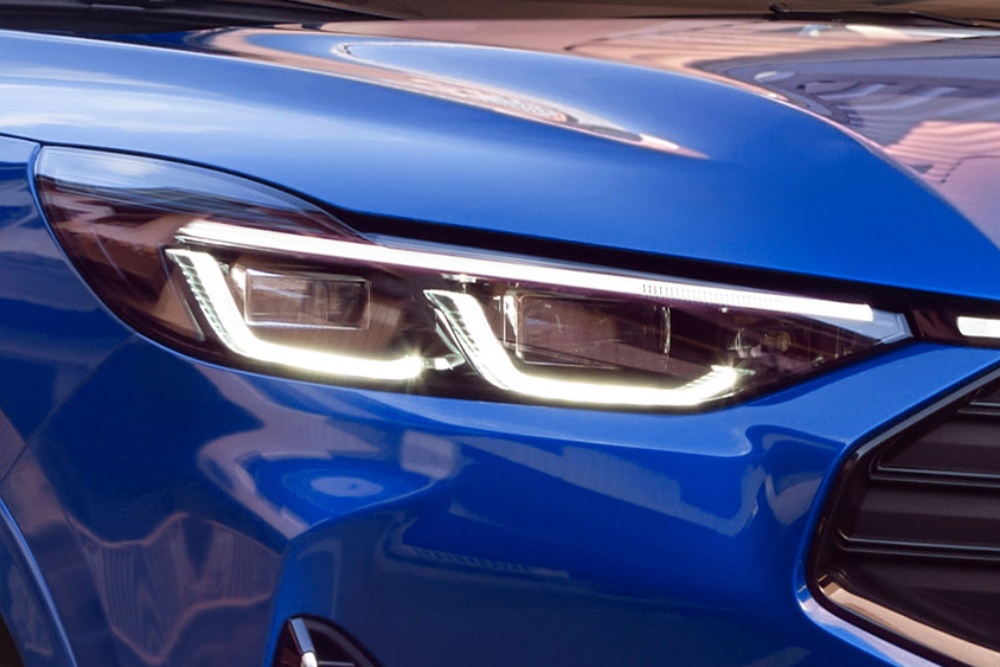 Grande plano do farol dianteiro de um Ford Mustang Mach-E azul.