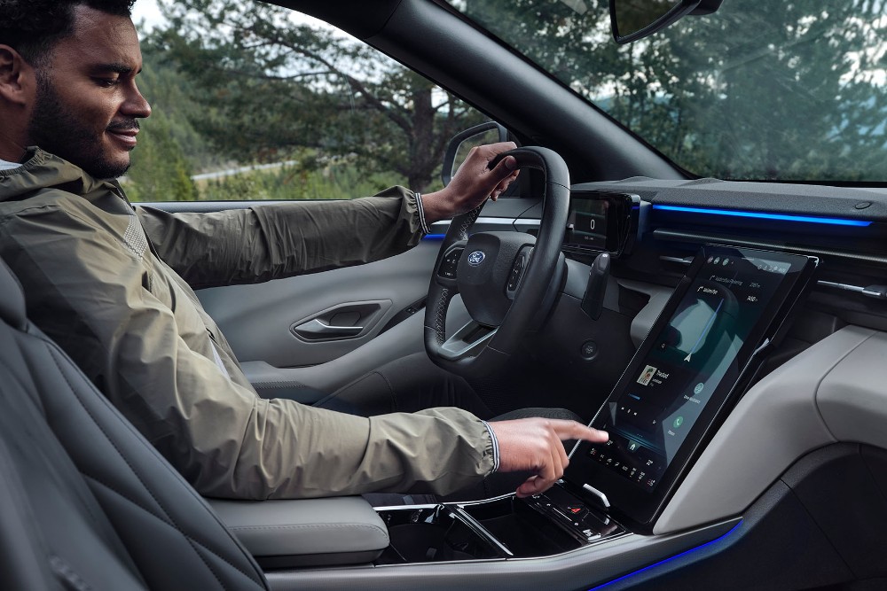 Homem sentado no banco do condutor do Ford Explorer, a interagir com o ecrã tátil grande do SYNC.
