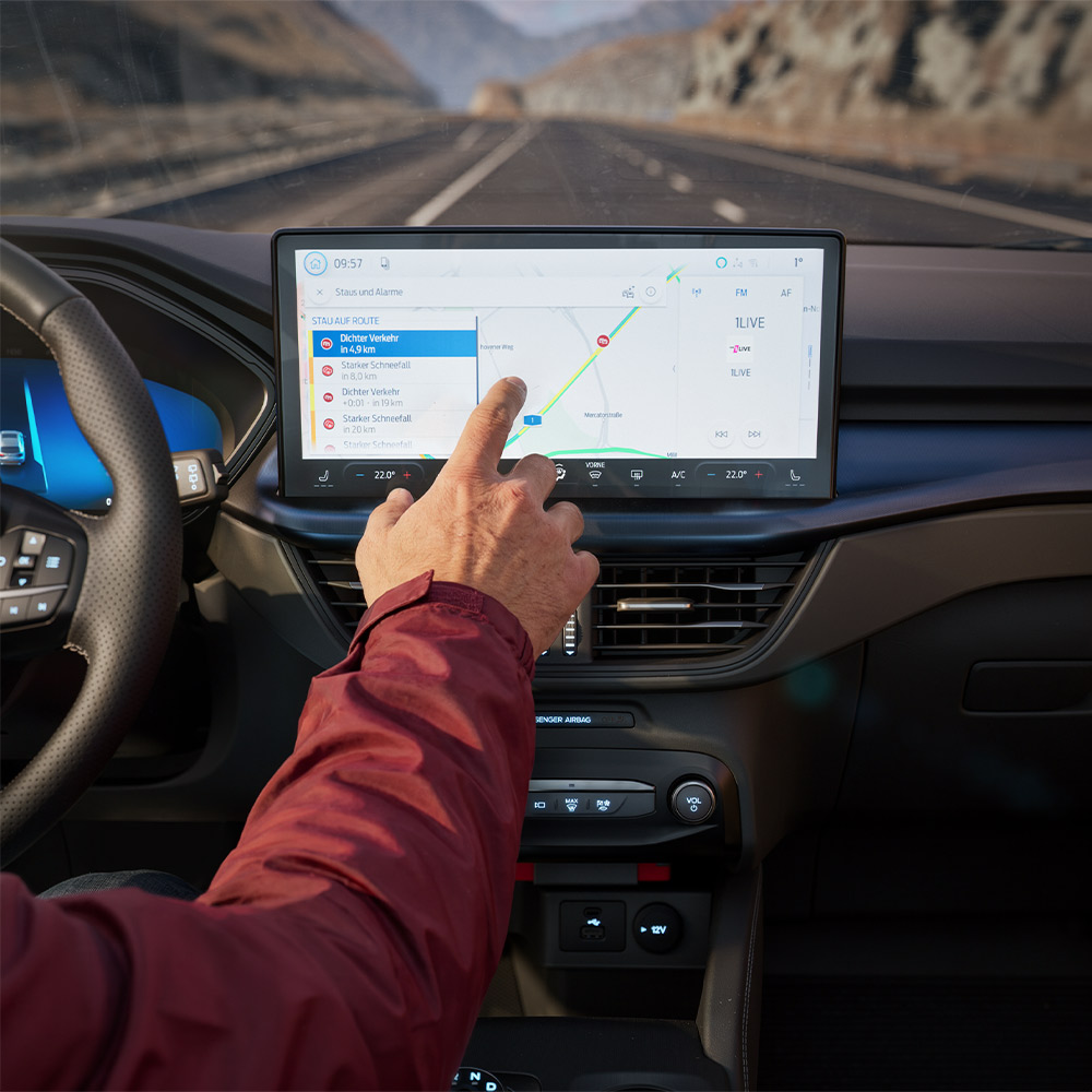 Um condutor a utilizar a funcionalidade de Navegação Conectada no ecrã digital de um Ford Kuga BlueCruise Edition.