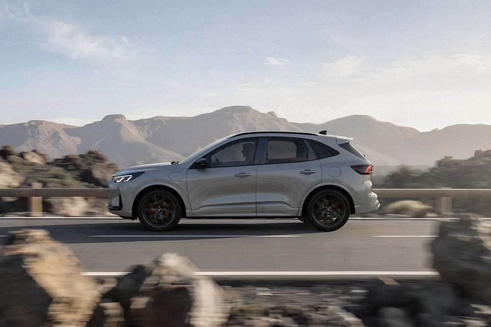 Um Ford Kuga prateado a percorrer uma estrada montanhosa panorâmica. 