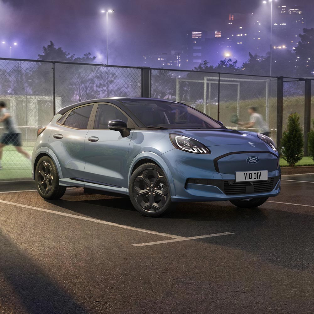 Um Ford Puma Gen-E edição limitada Vapour Blue, com tecnologia BlueCruise, estacionado junto a um campo de padel ao ar livre.