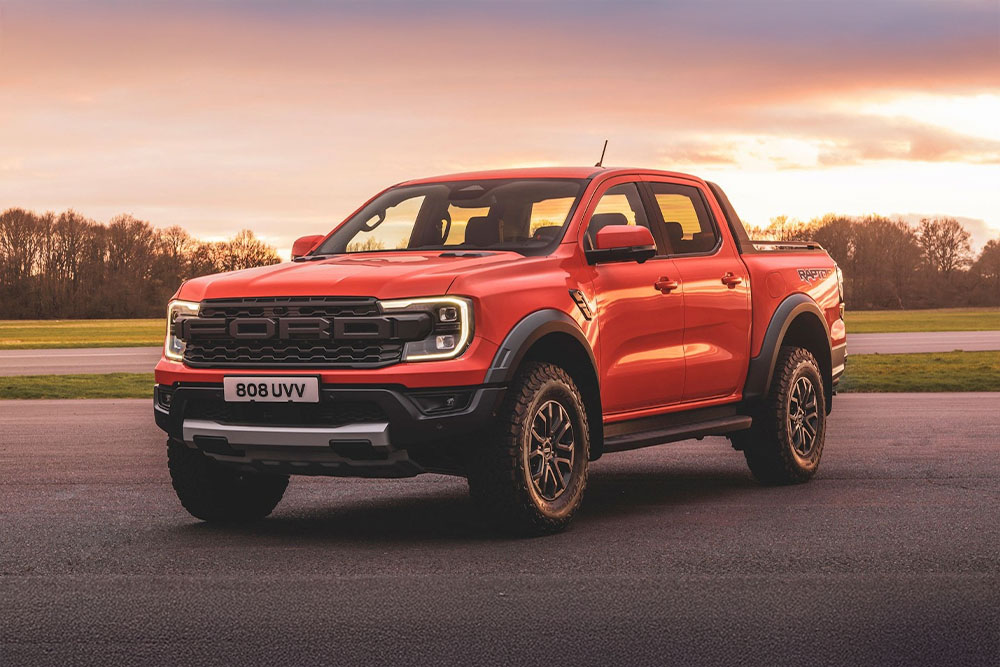 Uma pick-up Ford Ranger Raptor laranja estacionada em local panorâmico.