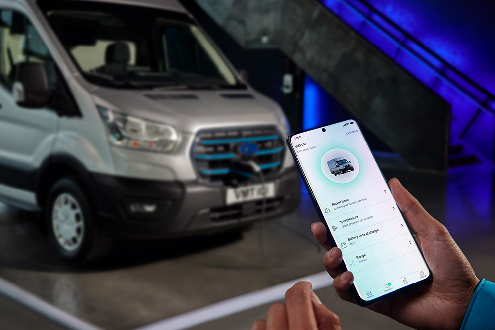 Telefone a mostrar o ecrã Ford app com a carrinha Ford E-Transit a carregar em segundo plano. 