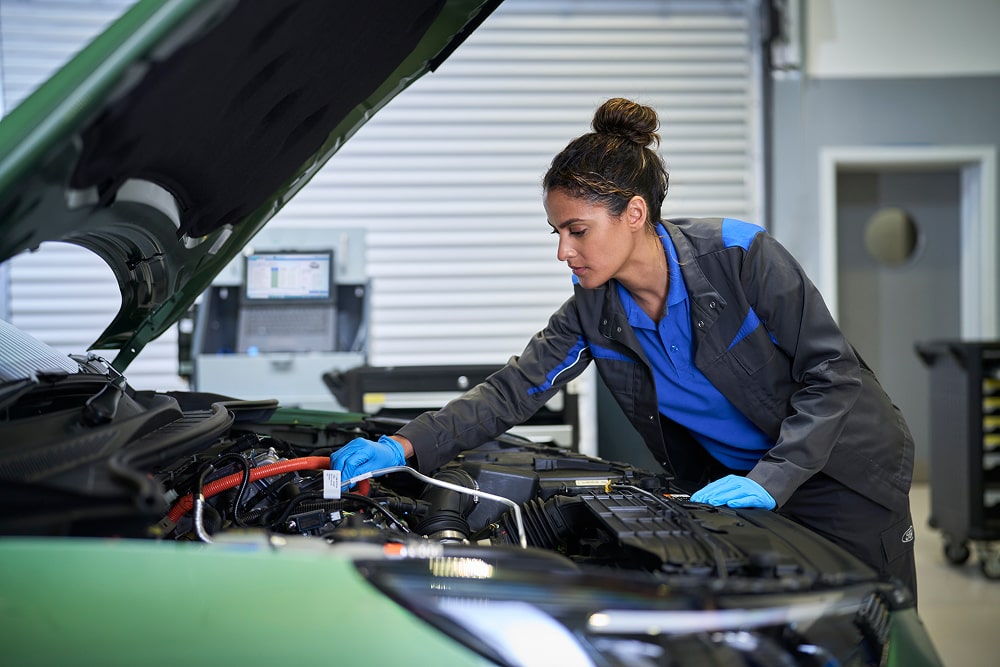 Mecânico da Ford a inspecionar o motor de um carro com o capô levantado numa garagem.